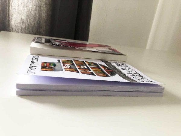 On the left is a gloss cover with a slight curl, and on the right is a matte cover that's curling. The book on the right is only a couple of months old.