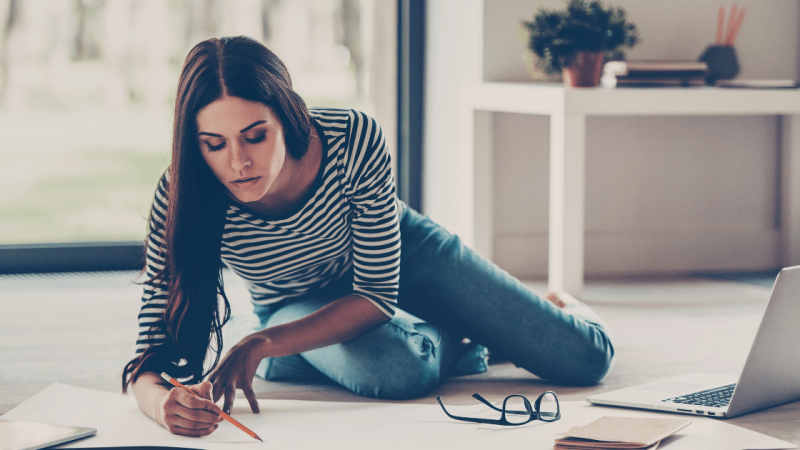 Woman multitasking between laptop and drawing