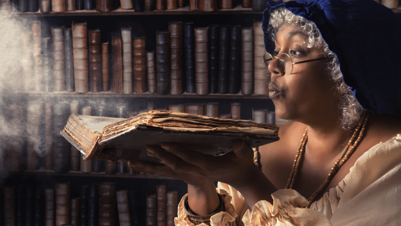 Woman blowing dust off a book